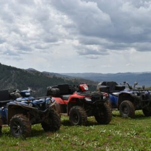 a group of four atvs parked on top of a lush green hillside
